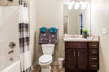A bathroom with a toilet sink and shower and a mirror